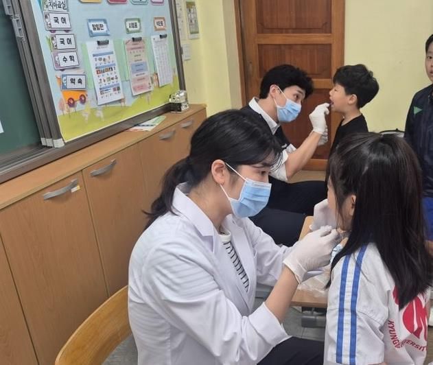 상록수보건소 치과의사와 치과위생사가 해양초등학교를 방문해 어린이들에게 불소도포를 진행하고 있다.