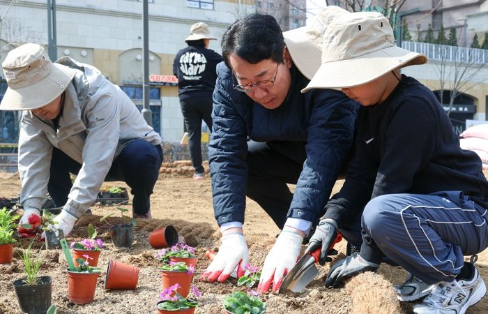 정명근 화성특례시장(가운데)이 21일 동탄여울공원에서 화성특별정원에 아이와 함께 꽃을 심고 있다