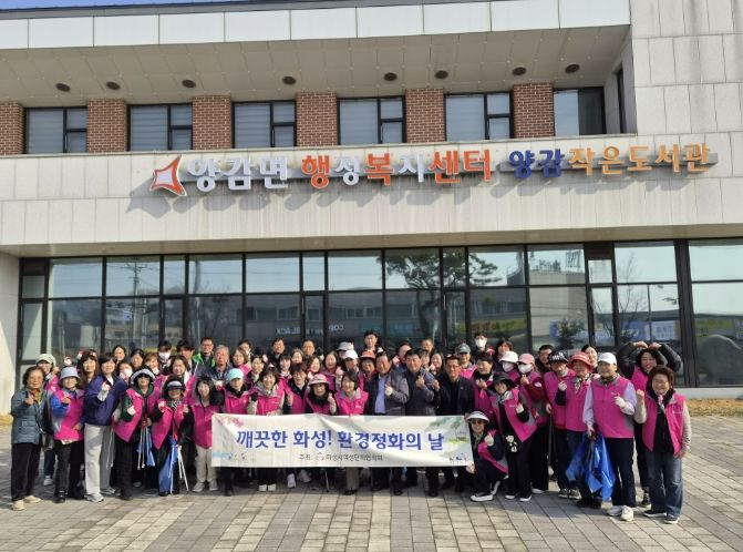 화성시여성단체협의회와 관계자들이 양감면 환경 정화 활동을 기념하고 있다